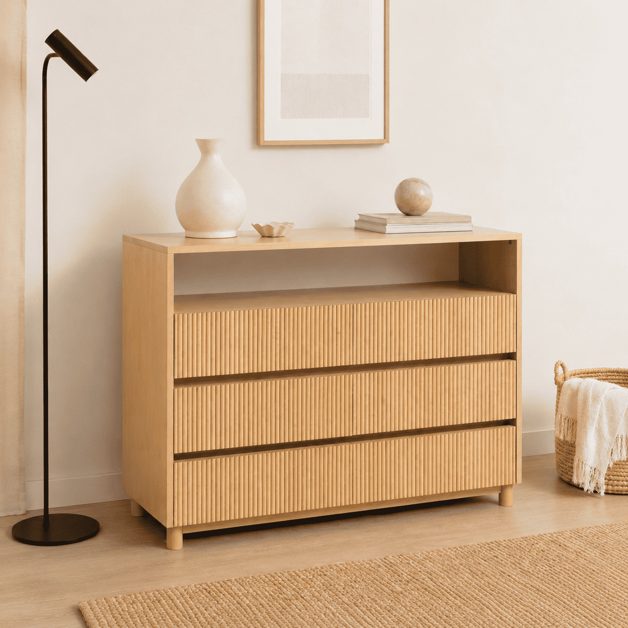 Cómoda cambiador de madera en color natural, con 3 cajones, listones verticales y un estante abierto, de diseño moderno.